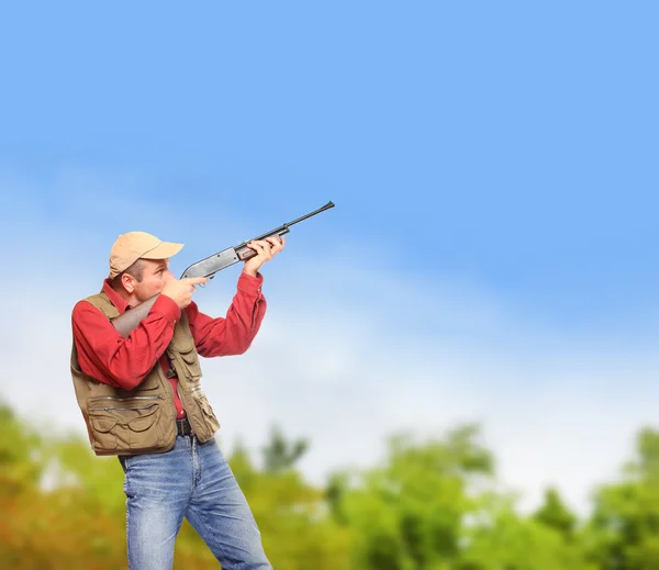 Охотник с охотничьим ружьем, нацеленным на голубое небо — стоковое фото
