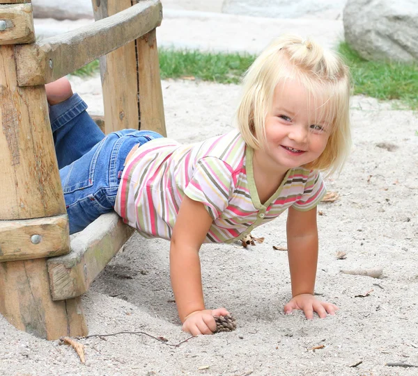Mała dziewczynka spadła do piasku na plac zabaw. — Zdjęcie stockowe