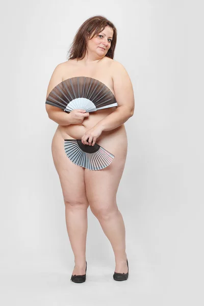 Femme nue en surpoids avec ventilateur pliant . — Photo