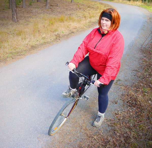 Overweight woman slimming on bicycle. — Stock fotografie