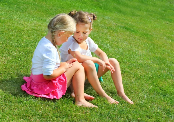 Zwei kleine Mädchen sitzen und reden auf Gras — Stockfoto