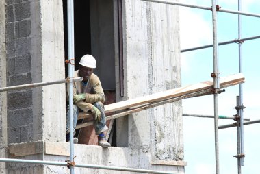 Unidentified African worker on a scaffold build new touristic resort clipart