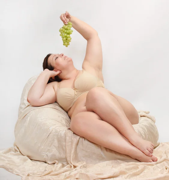 Mujer con sobrepeso comiendo uva . — Foto de Stock