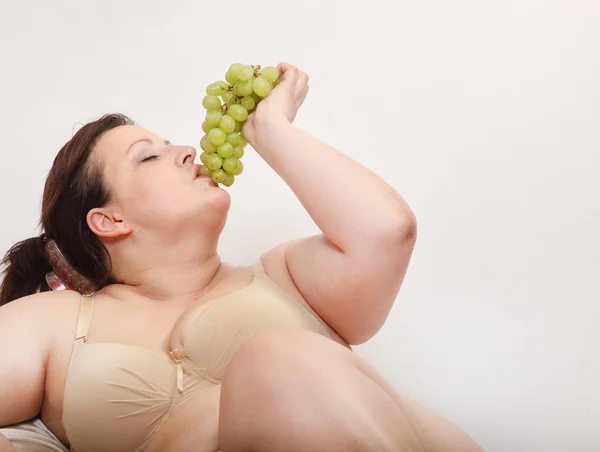 Mujer con sobrepeso comiendo uva . —  Fotos de Stock