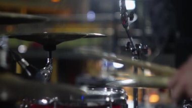 Sahne ışıkları altında davul setinde prova yapan müzisyen.