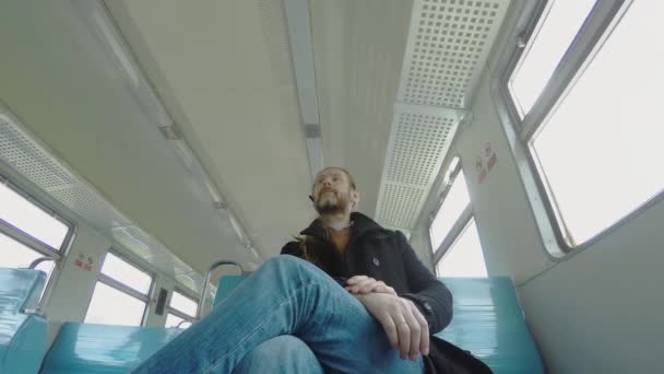 一头白胡子 一头金发 头戴蓝牙耳机 准备下火车 他扣上上衣 站起身来 走到车厢的出口 — 图库视频影像