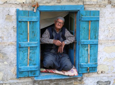 CAMLIYAYLA, ICEL, TURKEY-OCTOBER 30: Kimliği belirsiz yaşlı adam oturuyor ve Sebil Village 'deki evinin penceresinde poz veriyor. 30 Ekim 2016.