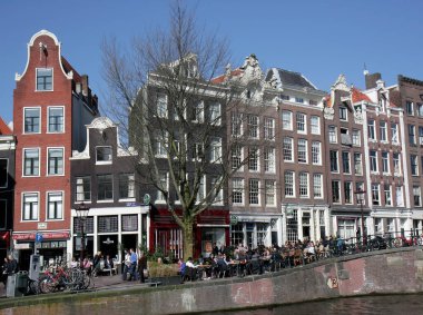 AMSTERDAM, NETHERLANDS-9 Mart: İnsanlar Kanal Evlerinin yanındaki Yerel Kafe 'de oturuyor ve güzel Bahar Gününün tadını çıkarıyorlar. 9 Mart 2014 Amsterdam, Hollanda.