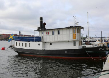 Stockholm, İsveç-18 Eylül 2025: Stockholm Belediye Binası 'nın oradaki limanda İsveç Bayrağı dalgalanan Eski Tekne