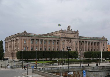 Stockholm, İsveç-18 Eylül 2025: İsveç bayrağı ve kimliği belirsiz kişilerin yürüdüğü parlamento binası