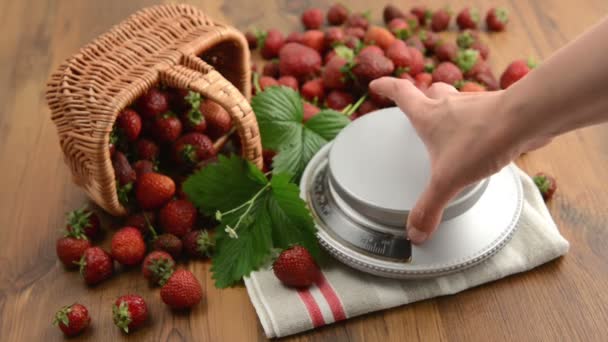 Erdbeeren im Korb auf einer kleinen Portion auf einer Gewichtswaage mit Blatt und Blütenkopf auf einem Holztisch. Marmelade kochen. — Stockvideo