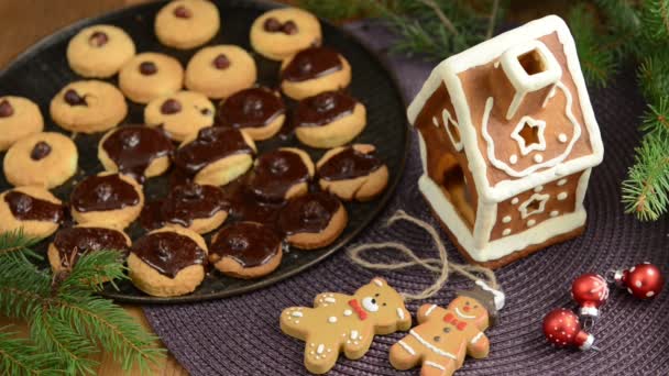 Karácsonyi sütési folyamat, piros golyó, karácsonyi dekoráció, sütemény. Mézeskalács házikó az asztalnál. — Stock videók