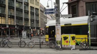 Hackescher Markt'taki Berlin bölgesi Mitte'de trafik. Teleferikler ve arabalar bir kavşakta geçerken. Sokaklarda yürüyen insanlar