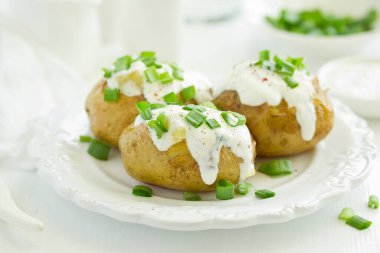 Peynirli fırında patates, ekşi krema ve soğanla servis ediliyor. Seçici odak