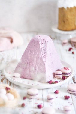 Geleneksel ortodoks süzme peynir tatlı paşası pembe makaronlu ve beyaz ahşap masa üzerinde çingene çiçekli.