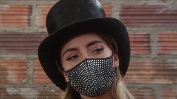 Giovane donna che indossa scintillante maschera nera contro muro di mattoni — Video Stock