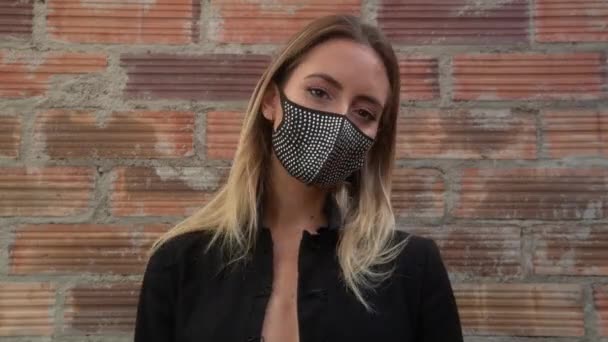 Giovane donna che indossa scintillante maschera nera contro muro di mattoni — Video Stock