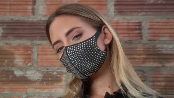 Młoda kobieta w błyszczącej czarnej masce na ścianie z cegły — Wideo stockowe