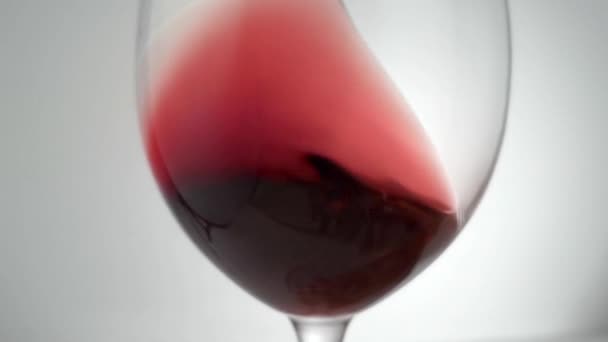 Zpomalený záběr vířícího červeného vína kolem skla — Stock video
