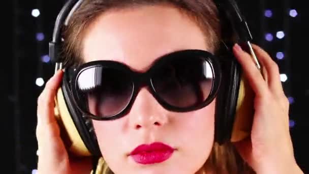 लड़की धूप का चश्मा और हेडफ़ोन पहनती — स्टॉक वीडियो