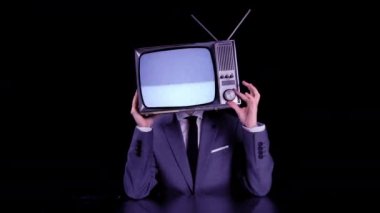 Kafasında TV olan takım elbiseli bir adam.