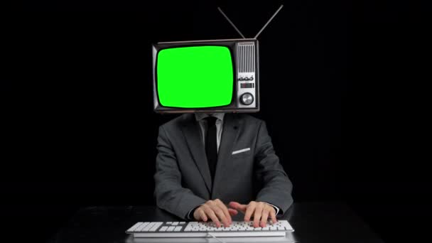 Man typing with TV on head showing green screen on the screen — Wideo stockowe