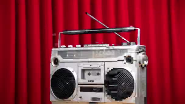 Spinnender Ghettoblaster gegen roten Samtvorhang — Stockvideo