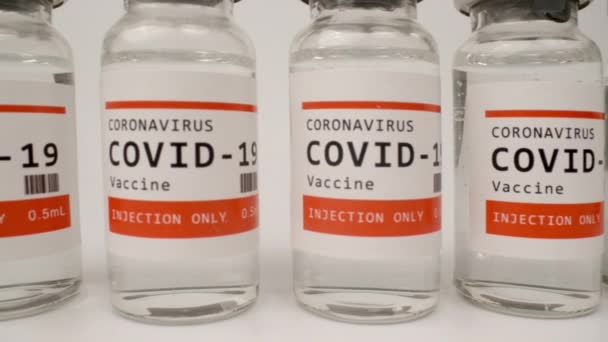 Glazen injectieflacons met het covid-19 vaccin tegen witte achtergrond — Stockvideo