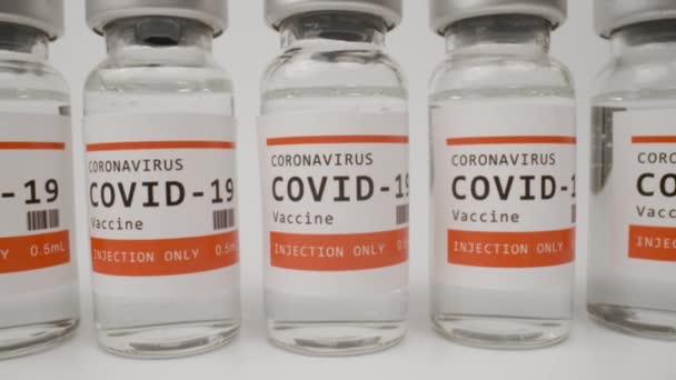 Glazen injectieflacons met het covid-19 vaccin tegen witte achtergrond — Stockvideo