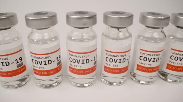 Glazen injectieflacons met het covid-19 vaccin tegen witte achtergrond — Stockvideo