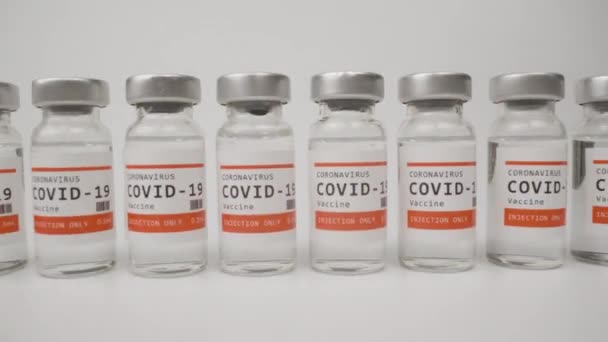 Glazen injectieflacons met het covid-19 vaccin tegen witte achtergrond — Stockvideo