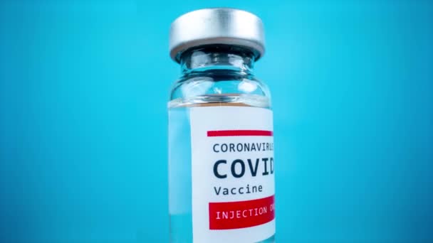 Glazen injectieflacon met het covid-19 vaccin tegen blauwe achtergrond — Stockvideo