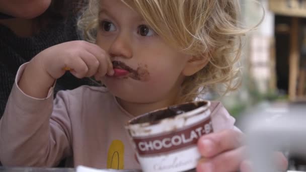 Девочка ест шоколадное мороженое — стоковое видео