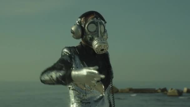 輝くガスマスクをした男が海で踊る — ストック動画