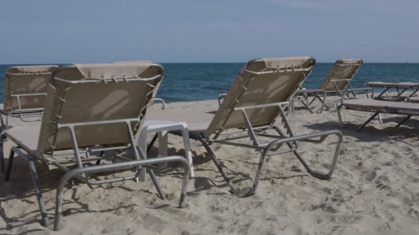 Ligstoelen gestapeld op het strand — Stockvideo