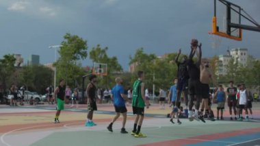 Dışarıda basketbol oynayan genç yetişkinler.