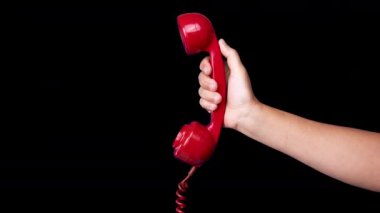 Elinde retro kırmızı bir telefonun alıcısı var.