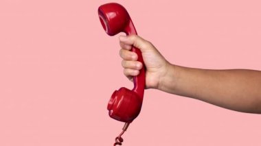 Elinde retro kırmızı bir telefonun alıcısı var.