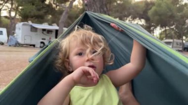 Babasıyla hamakta kamp yapan bir çocuk.