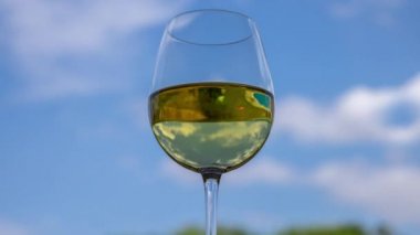 Mavi gökyüzüne karşı bir kadeh beyaz şarap
