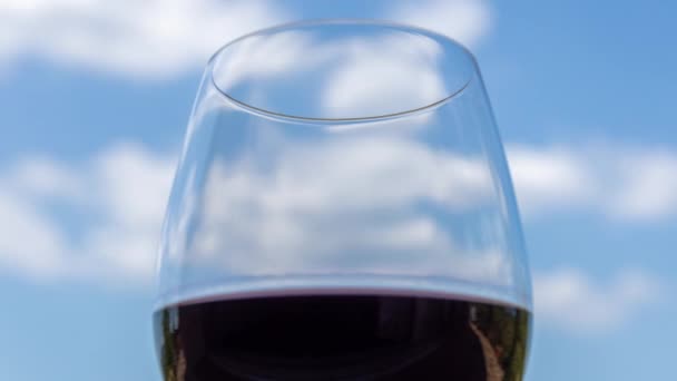 Glas rode wijn tegen de blauwe lucht — Stockvideo