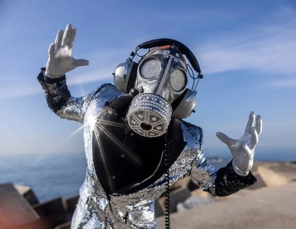 Man with sparkling gas mask dancing by the sea — Stock Photo, Image