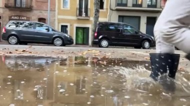 Tatlı küçük kız yağmur birikintisinde atlıyor.