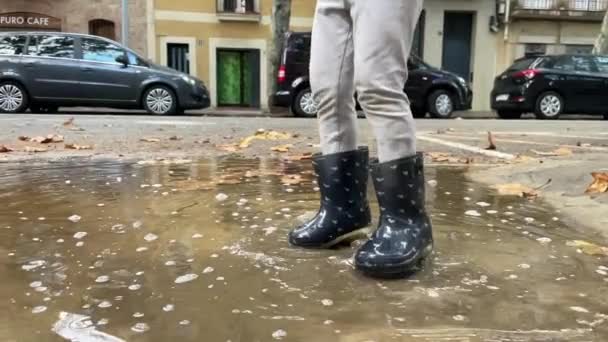 Schattig klein meisje springen in regen plas — Stockvideo