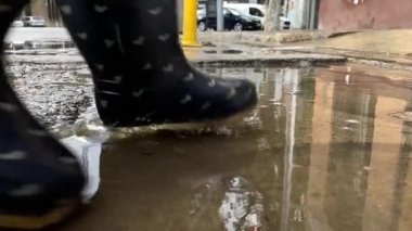 Tatlı küçük kız yağmur birikintisinde atlıyor.