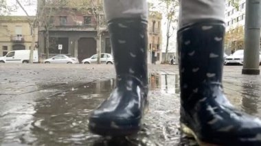 Tatlı küçük kız yağmur birikintisinde atlıyor.