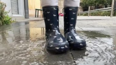 Tatlı küçük kız yağmur birikintisinde atlıyor.