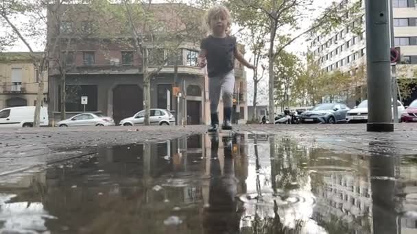 Gadis kecil yang lucu melompat di genangan hujan — Stok Video