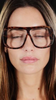 Siyah arka planda dikey gözlüklü güzel bir kadın. 