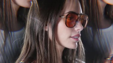 Güneş gözlüklü güzel bir kadın etrafa bakıyor.